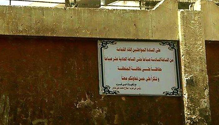 تعليق لوحة لتحديد موعد إلقاء القمامة بجوار مدرسة في أسيوط